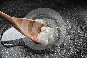 Wooden spoon with coconut oil in frying pan