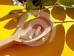 Wooden spoon, collagen nutrition  ascorbic  supplement  on a colored background