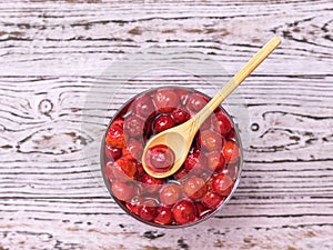 Wooden spoon in a Cup of freshly made cherry jam on a wooden background. Flat lay.