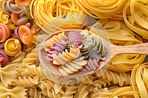 Wooden spoon and different types of pasta as background