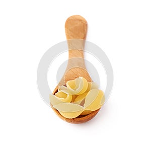 Wooden spoon filled with dry conchiglie pasta over isolated white background