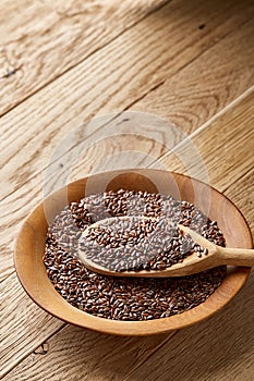 Wooden spoon with flax seeds on rustic background, top view, close-up, shallow depth of field, selective focus