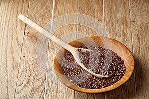 Wooden spoon with flax seeds on rustic background, top view, close-up, shallow depth of field, selective focus