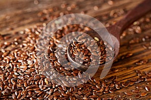 Wooden spoon with flax seeds on rustic background, top view, close-up, shallow depth of field, selective focus