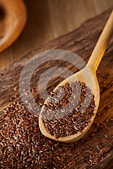 Wooden spoon with flax seeds on rustic background, top view, close-up, shallow depth of field, selective focus