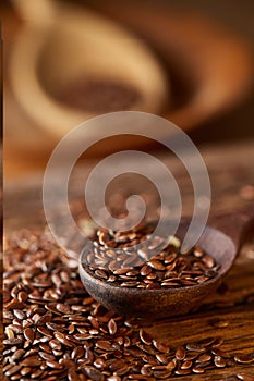 Wooden spoon with flax seeds on rustic background, top view, close-up, shallow depth of field, selective focus