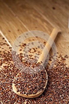 Wooden spoon with flax seeds on rustic background, top view, close-up, shallow depth of field, selective focus, vertical