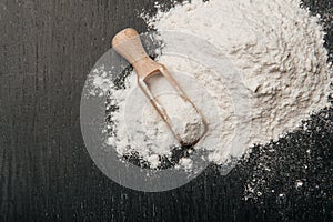 Wooden spoon with flour on a black background