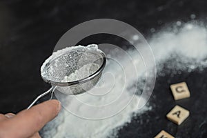 A wooden spoon with flour and wooden letters