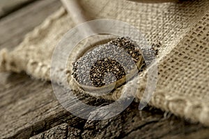 Wooden spoon full of chia seeds lying on a linen textile