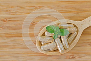 Wooden spoon full of herbal medicine in clear capsules, ideal for Homeopathic remedies