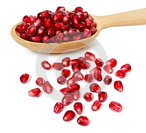 Wooden spoon full of pomegranate seeds, isolated on white background