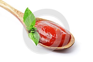 Wooden spoon full of tomato sauce with fresh basil isolated