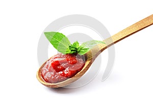 Wooden spoon full of tomato sauce with fresh basil isolated on white