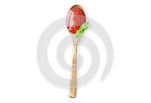Wooden spoon full of tomato sauce with fresh basil isolated on white