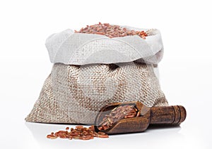 Wooden spoon and linen bag of raw organic red rice on white background. Healthy food