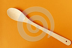 Wooden spoon on an orange  background. Close-up