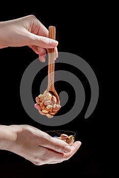 Wooden spoon with peanut butter and peanuts on a black background