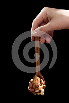 Wooden spoon with peanut butter and peanuts on a black background