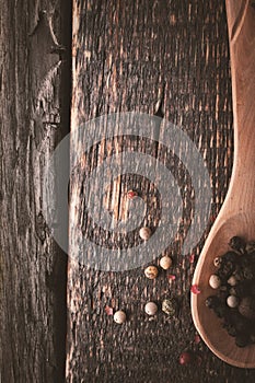 Wooden spoon with pepper mix on the wooden background vertical
