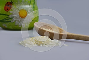 Wooden spoon with pile of rice and a jar