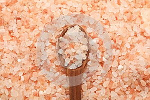 Wooden spoon on pink himalayan salt background