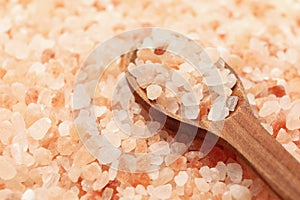 Wooden spoon on pink himalayan salt background