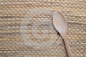 Wooden spoon placed on traditional wickerwork texture.