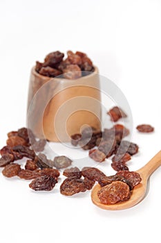 Wooden spoon with raisins and wooden bowl on a white background