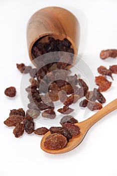 Wooden spoon with raisins and wooden bowl on a white background