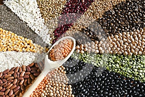 Wooden spoon with raw red lentils on various grain