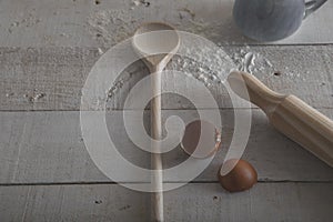 Wooden spoon and rolling pin to make the dough, flour and egg. Preparation of the dough on white wooden background. Isolated image