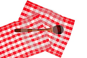 A wooden spoon with safran spice threads on a red checkered tablecloth or napkin isolated on white. Healthy eating and nutrition. photo