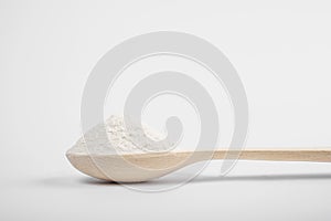 Wooden spoon with a slide of flour on a white background. macro side view. ingredients for making desserts, pastries, bread, cake,