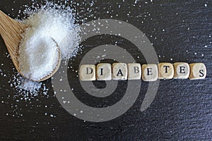 Wooden spoon with sugar and diabetes word written on wooden cubes