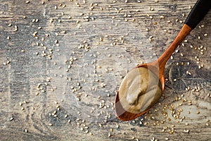 Wooden spoon with tahini on wooden table.