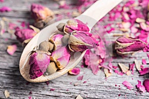 Wooden spoon with tea rose buds and petals