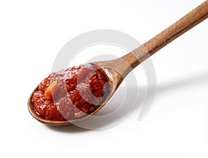 Wooden spoon and tomato sauce on white background