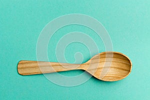 Wooden spoon on a turquoise background.Spoon with textured tree. Trend Colors . Copy space