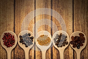 Wooden spoons agaisnt rustic background,with colored berries and seeds