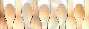 Wooden spoons aligned on white panoramic background, plastic free environment friendly disposable cutlery web banner
