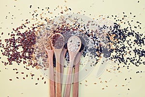 Wooden spoons with assorted seeds isolated on yellow background, chia, linen sesame, healthy food supplements, top view