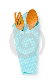 Wooden spoons and fork in a blue cloth on white background, Cli