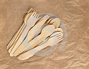 Wooden spoons, forks, knives on the background of crumpled kraft paper. Ecology, the concept of zero waste. Top view