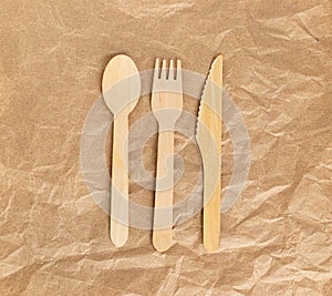 Wooden spoons, forks, knives on the background of crumpled kraft paper. Ecology, the concept of zero waste. Top view