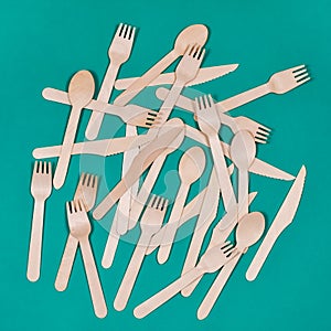 Wooden spoons, forks, knives on a green background. Zero waste concept.