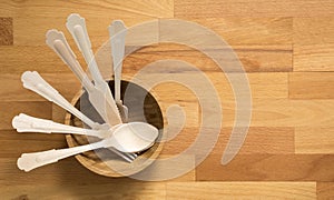 Wooden spoons, forks and knives in wooden bowl on wooden background