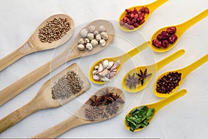 Wooden spoons full of aromatic herbs and spices on a white fabr photo