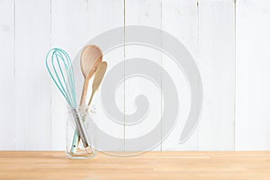 Wooden spoons and green colored whisker in a glass jar