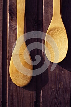 Wooden spoons one shorter than the other hang on a wooden Burgundy wall